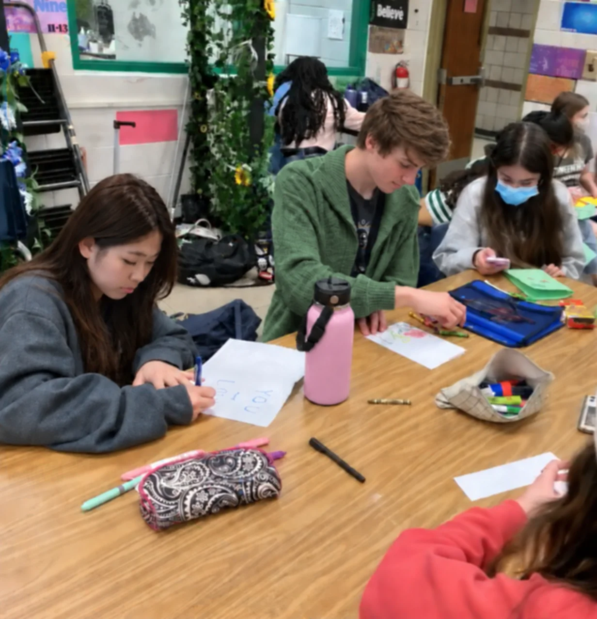 Students drawing and writing care cards together at a classroom table