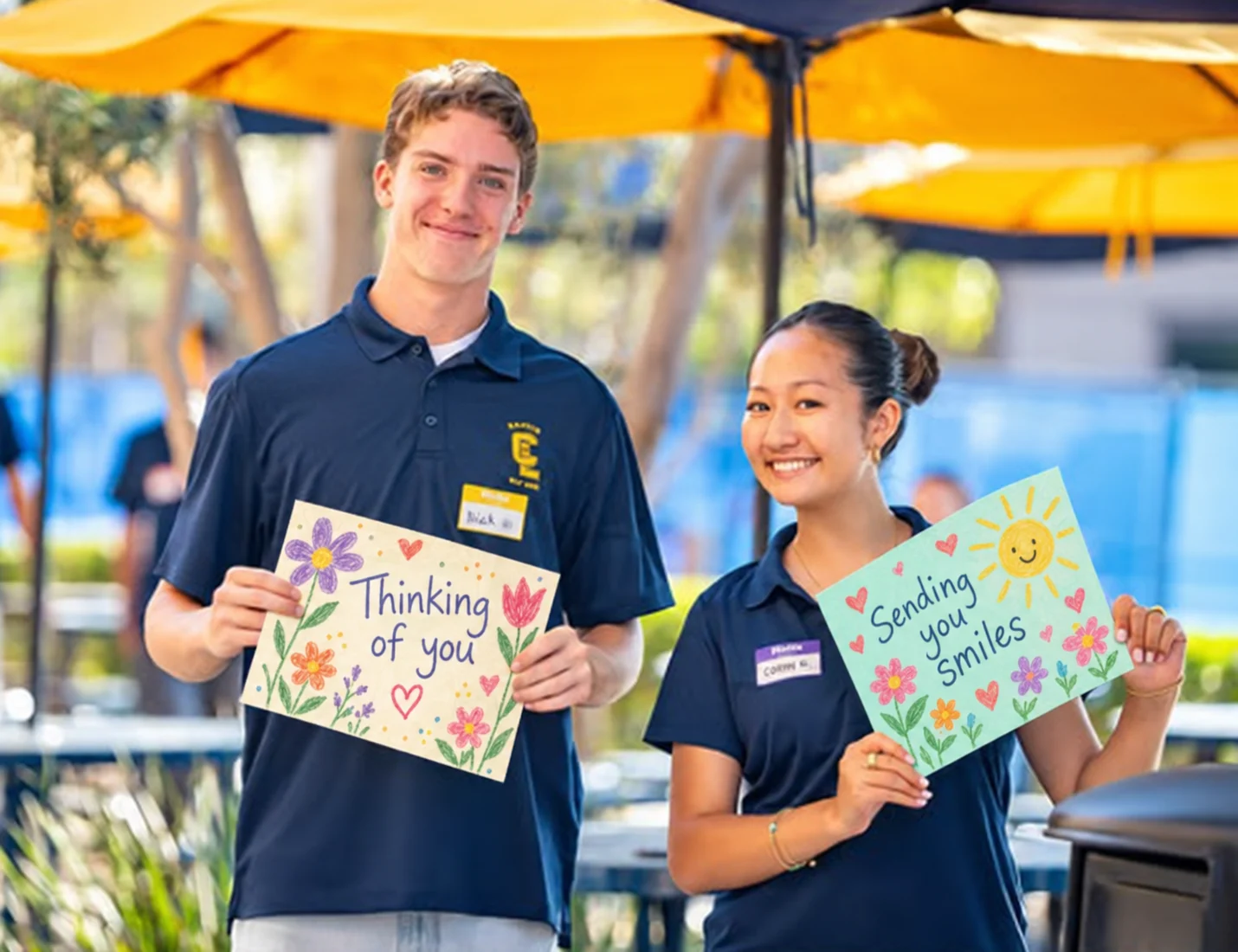 Two volunteers proudly holding colorful cards outdoors