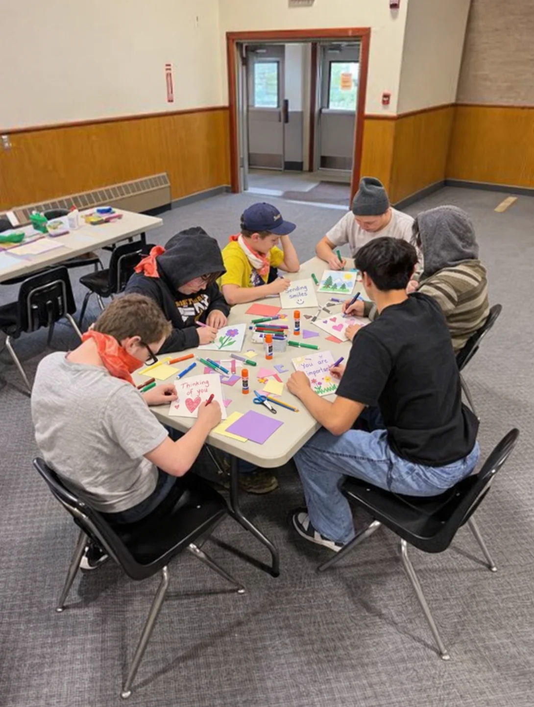 Students gathered around a table decorating handmade cards
