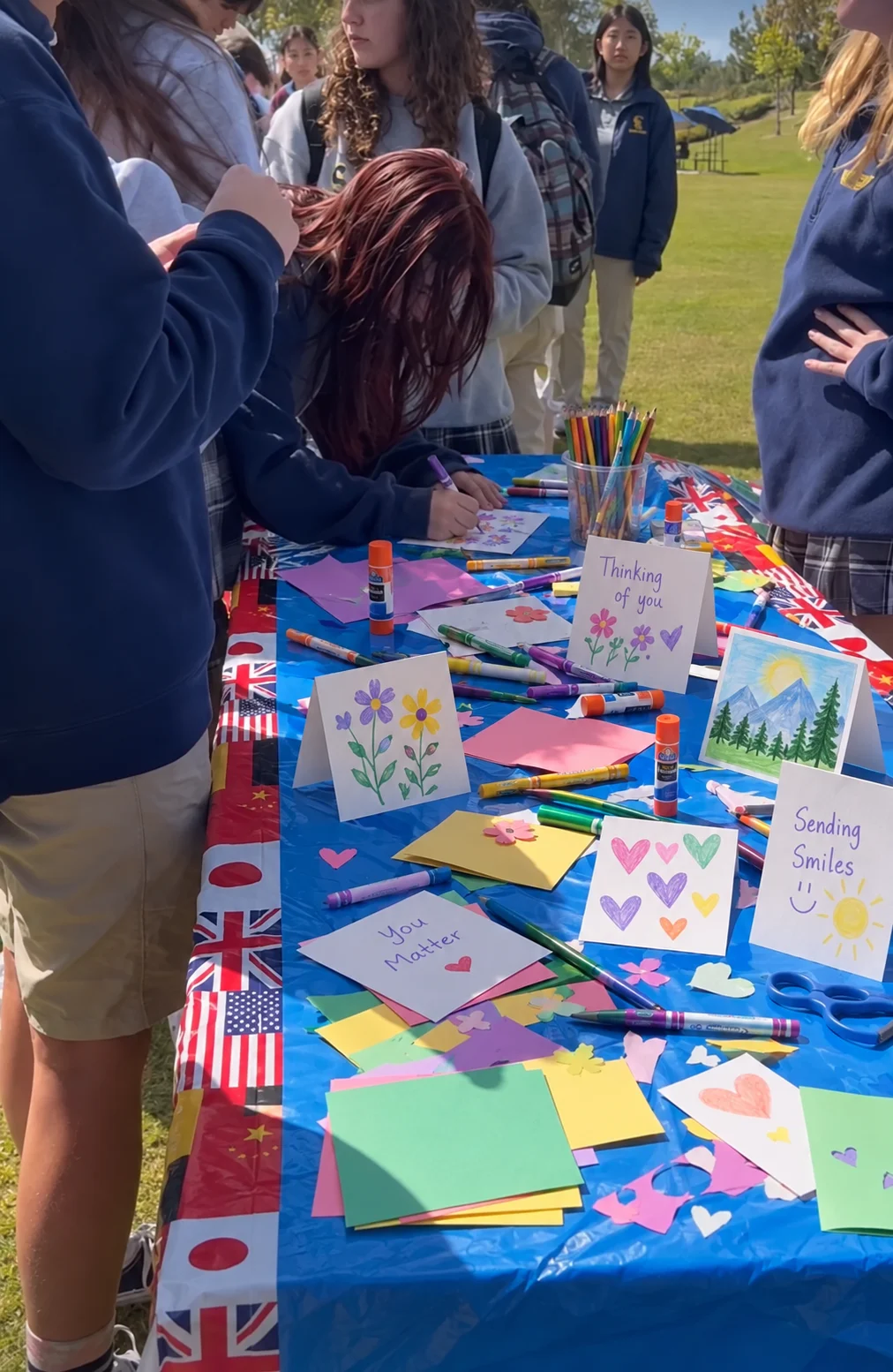 An outdoor card-making table filled with handmade cards and art supplies
