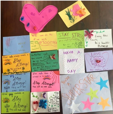 Handmade sample cards with colorful paper hearts, flowers, rainbows, stars, and encouraging messages