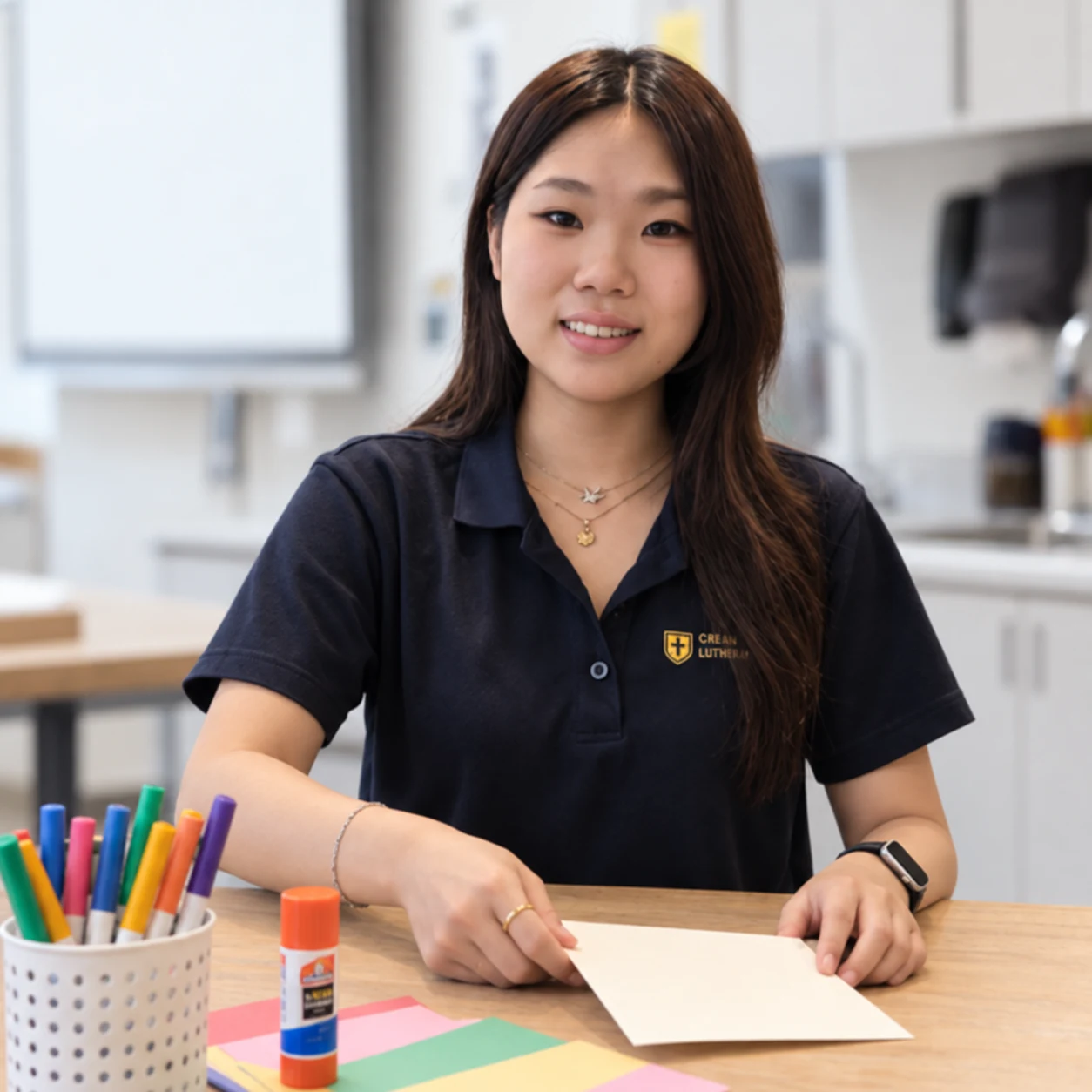 Jeemin at the classroom craft table in her Crean Lutheran uniform